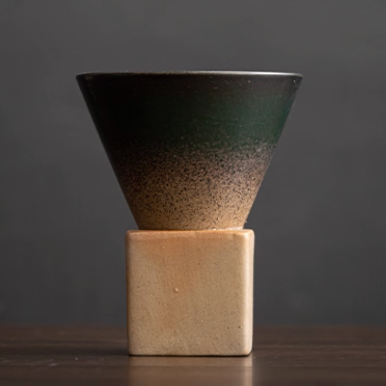 Ceramic cone-shaped coffee cupl with gradient finish on a square base against a dark background