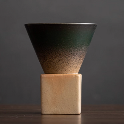Ceramic cone-shaped coffee cupl with gradient finish on a square base against a dark background