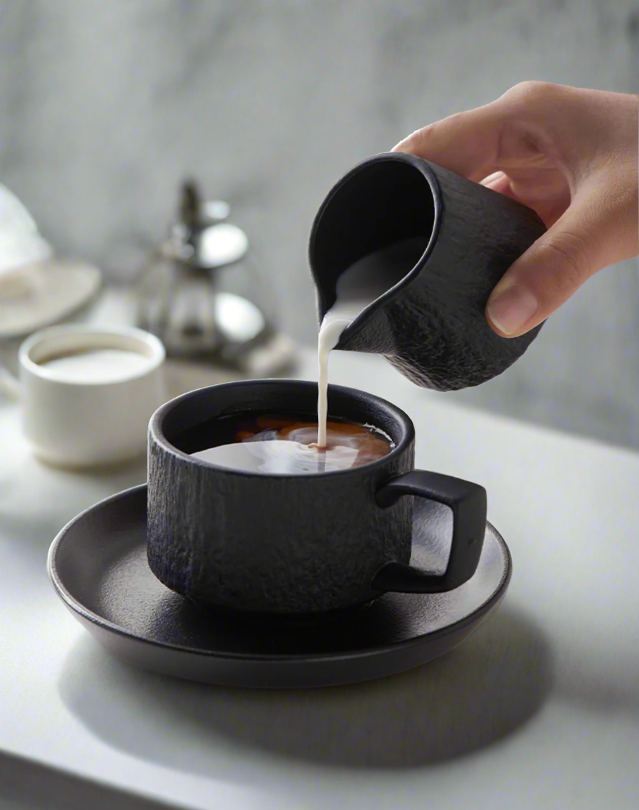 Close-up ceramic creamer showing handle and spout craftsmanship detail